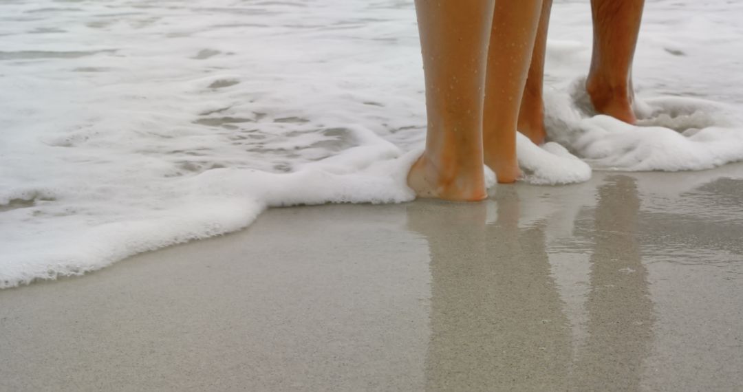 Couple Standing Barefoot at Water's Edge on Beach