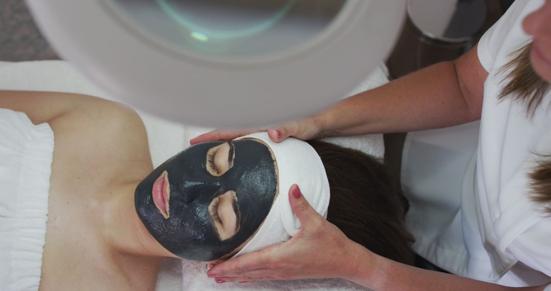 Woman Receiving Face Treatment with Black Facial Mask in Spa - Free Images, Stock Photos and Pictures on Pikwizard.com