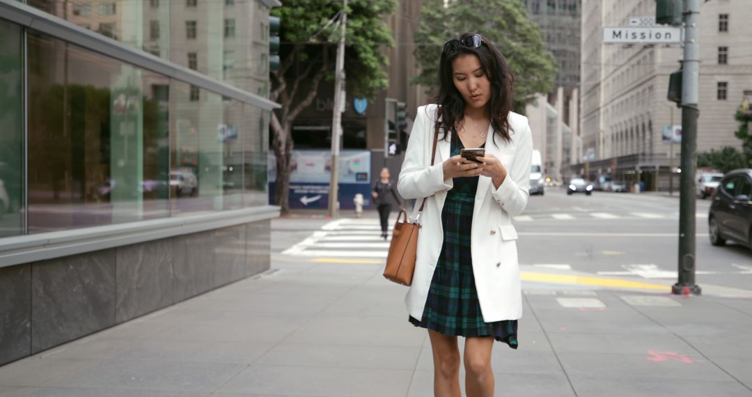 Young Asian woman checks her phone on a city street, with copy space - Free Images, Stock Photos and Pictures on Pikwizard.com