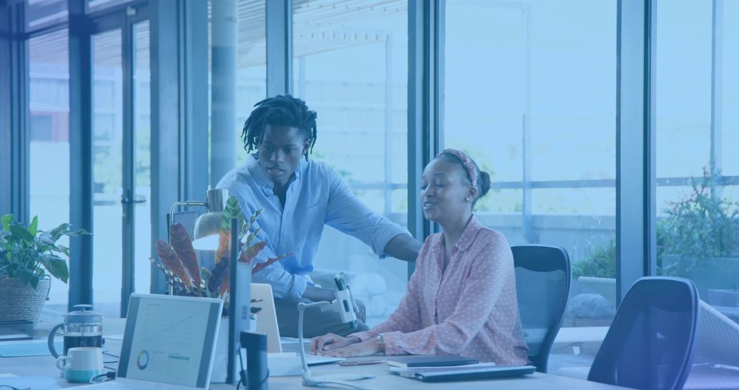 Collaborating professionals reviewing charts on monitor in modern daylight office workspace