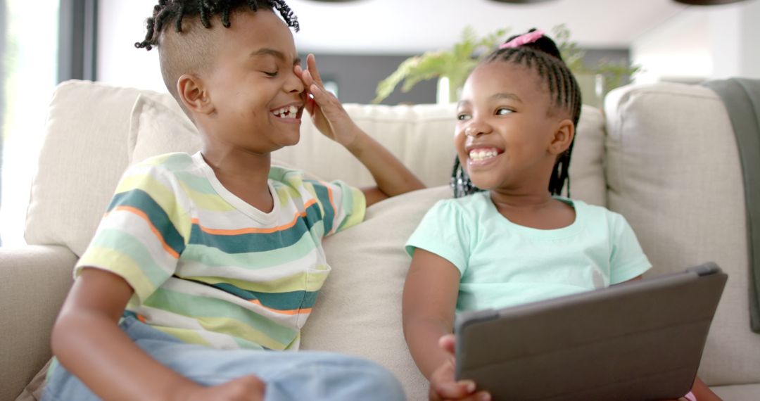 African American Siblings Enjoying Tablet at Home in Playful Mood