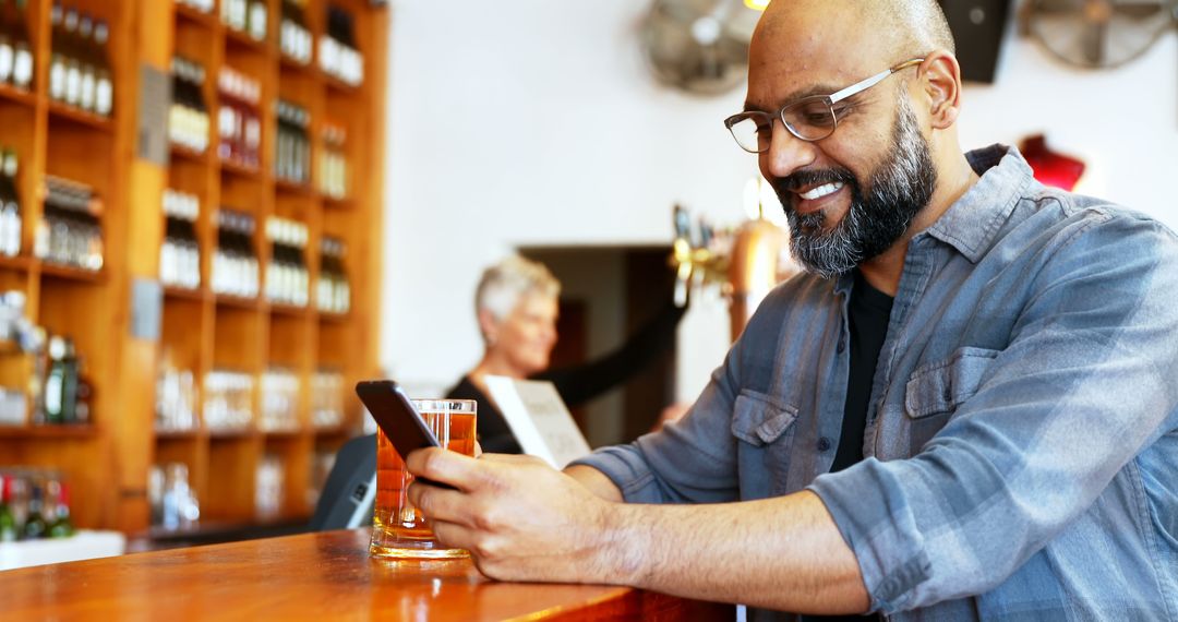 Middle-Aged Man at Bar Using Smartphone and Drinking Beer