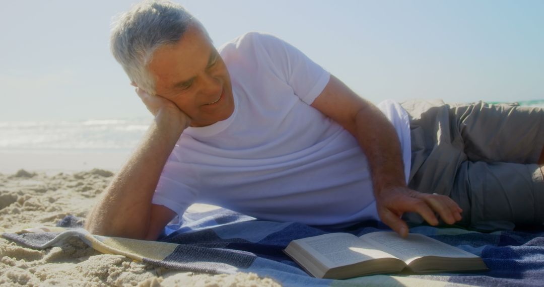 Senior Man Relaxing and Reading on Sandy Beach