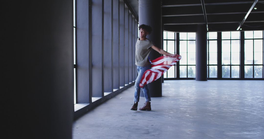 Young Person Joyfully Holding a Striped Fabric in a Spacious Empty Building - Free Images, Stock Photos and Pictures on Pikwizard.com