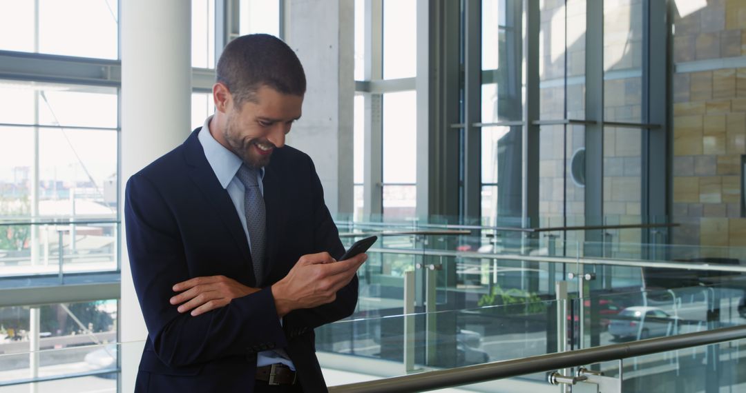 Smiling businessman using smartphone in modern office building - Free Images, Stock Photos and Pictures on Pikwizard.com