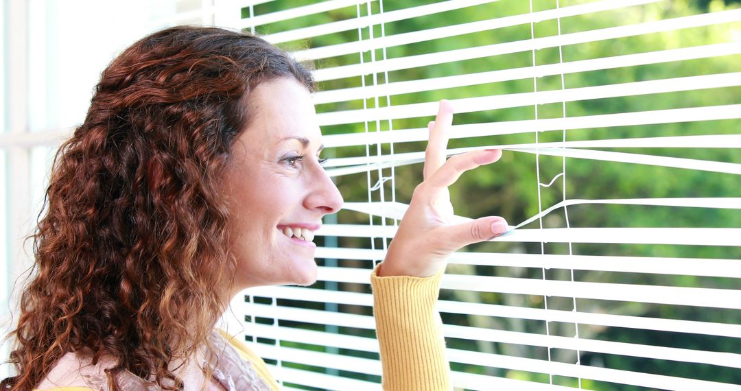 Woman Peeking Through Window Blinds on a Sunny Day - Free Images, Stock Photos and Pictures on Pikwizard.com