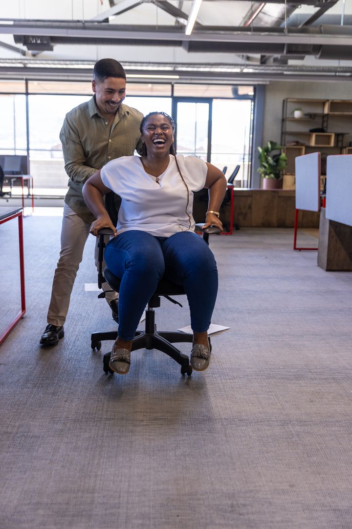 Coworkers Enjoying Office Fun with Rolling Chair Activity