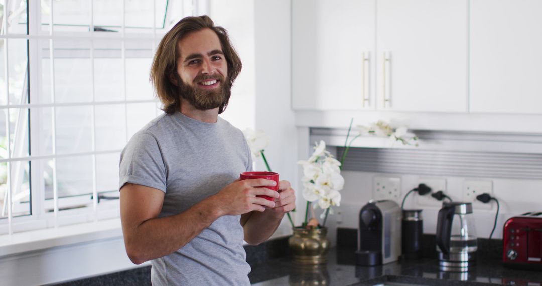 Smiling Young Man Drinking Coffee in Kitchen - Free Images, Stock Photos and Pictures on Pikwizard.com