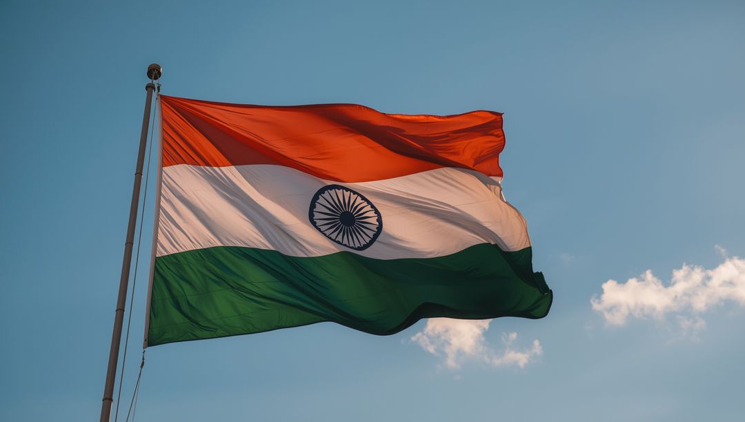 Indian National Flag Waving Against Blue Sky and Clouds