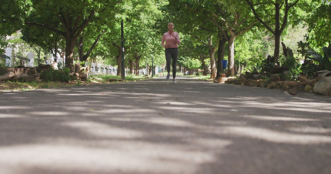 Woman Running on Tree-Lined Pathway in Outdoor Park - Free Images, Stock Photos and Pictures on Pikwizard.com