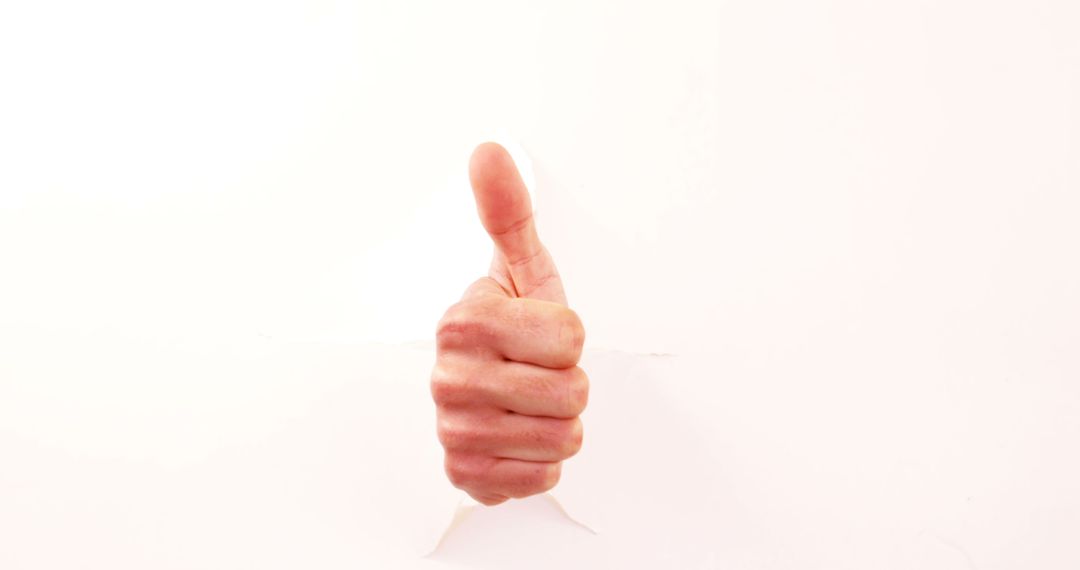 Thumbs Up Hand Gesture Breaking Through White Paper - Free Images, Stock Photos and Pictures on Pikwizard.com