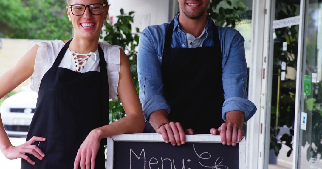 Smiling waiter and waitress standing with menu board outside the cafe 4k - Free Images, Stock Photos and Pictures on Pikwizard.com