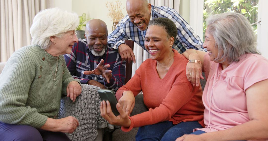 Senior Friends Laughing Together at Smart Phone Screen Indoors - Free Images, Stock Photos and Pictures on Pikwizard.com