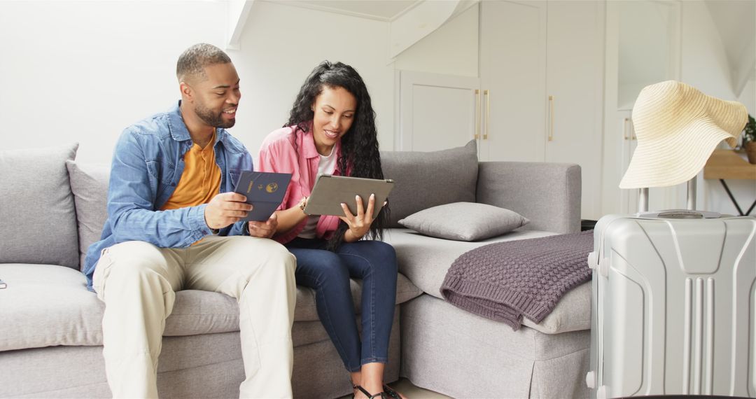 Couple Planning Vacation with Suitcase and Tablet at Home
