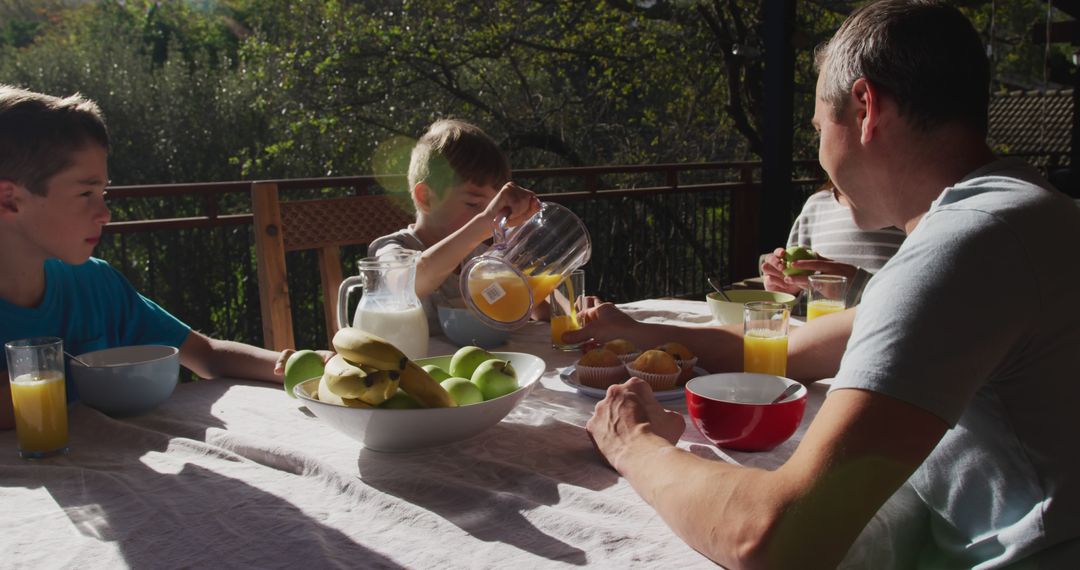 Family Having Breakfast on Sunny Balcony With Fresh Juice and Fruits - Free Images, Stock Photos and Pictures on Pikwizard.com