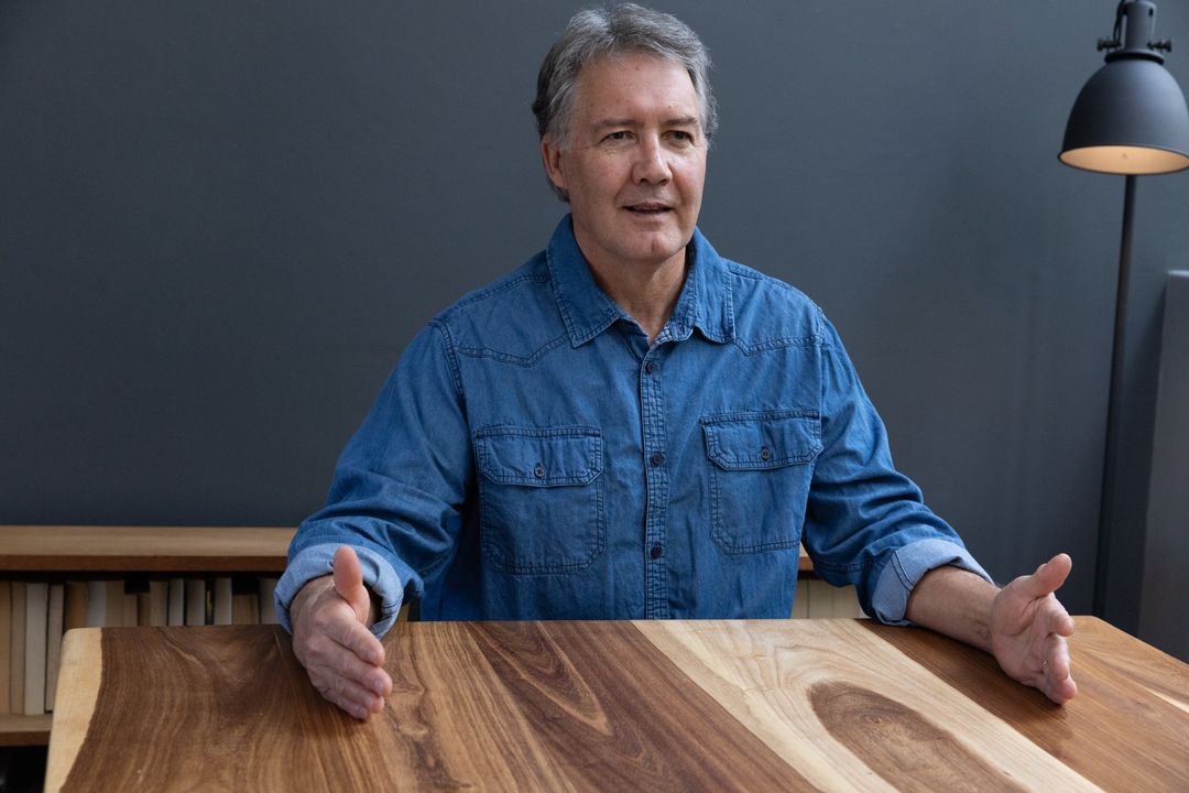 Mature Man Discussing Work at Wooden Table in Modern Workspace