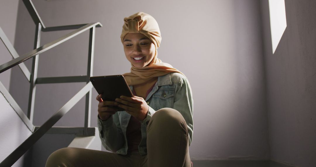 Smiling Woman in Hijab Using Tablet on Staircase - Free Images, Stock Photos and Pictures on Pikwizard.com