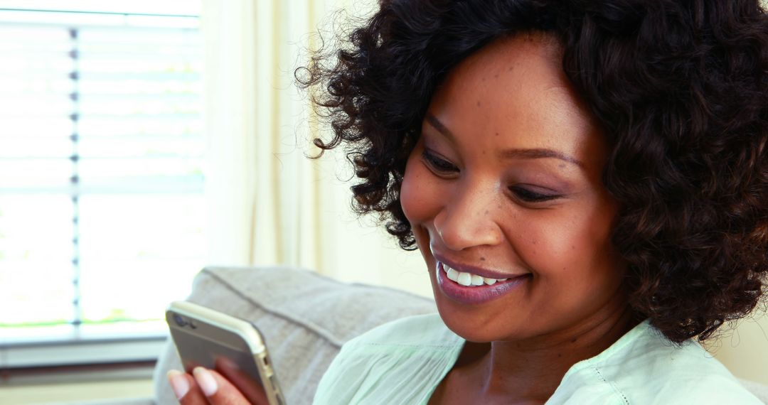 Smiling African American Woman Enjoying Smartphone at Home - Free Images, Stock Photos and Pictures on Pikwizard.com