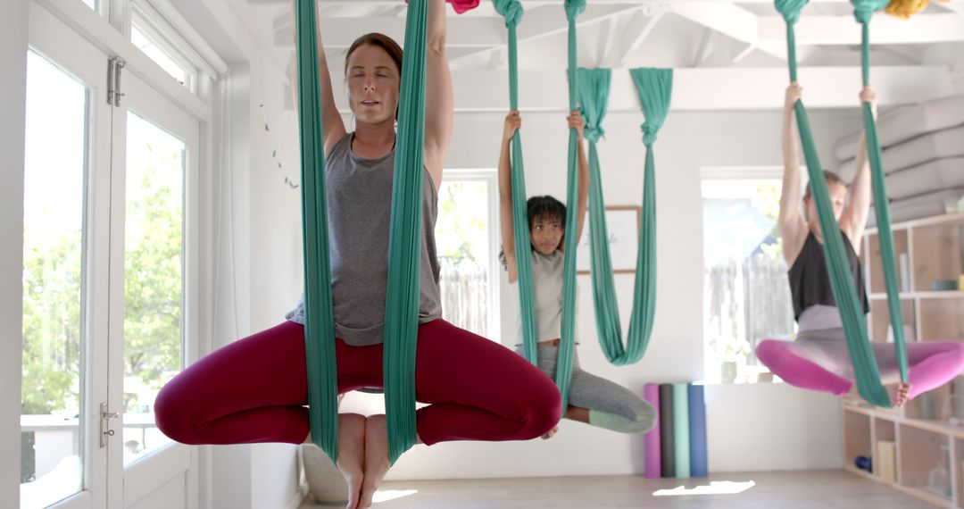 Group Aerial Yoga Class Performing Silk Hammock Poses in Studio - Free Images, Stock Photos and Pictures on Pikwizard.com