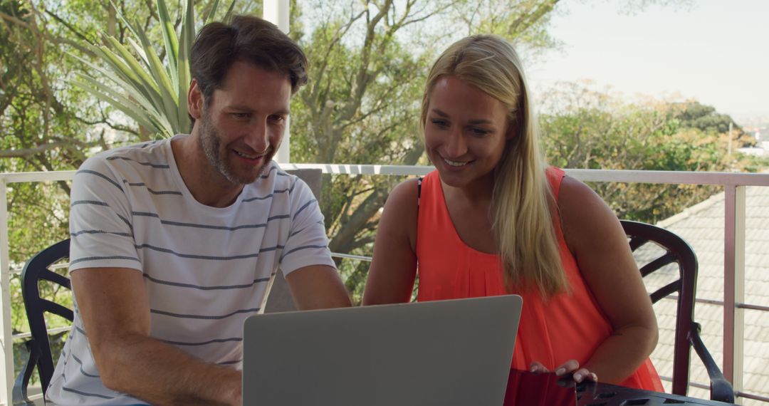 Smiling Couple Using Laptop in Outdoor Patio Area - Free Images, Stock Photos and Pictures on Pikwizard.com