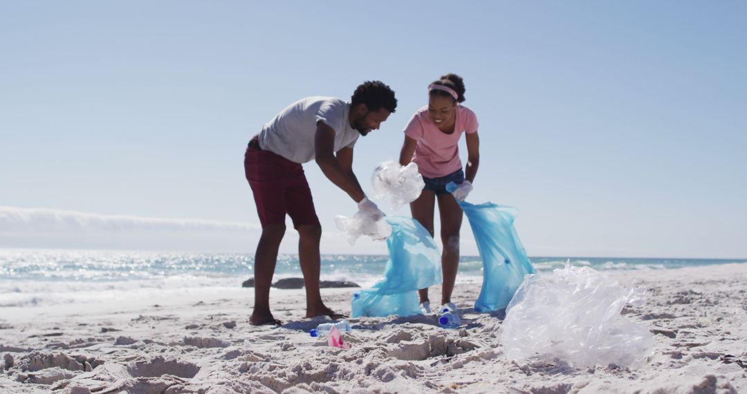African american couple collecting plastic waste on the beach - Free Images, Stock Photos and Pictures on Pikwizard.com