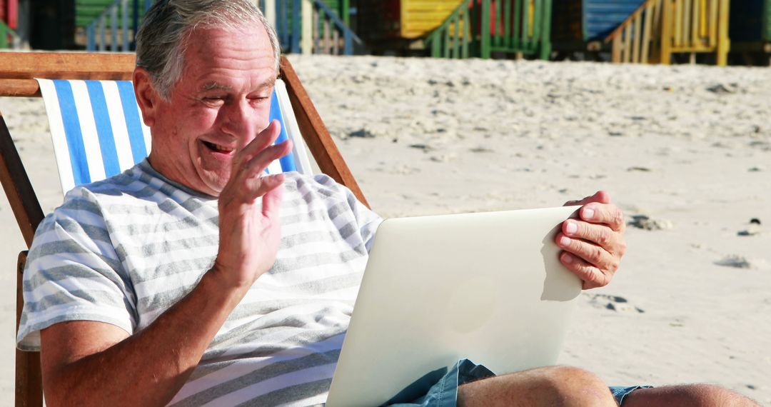 Senior Man Waving During Video Call On Beach With Laptop - Free Images, Stock Photos and Pictures on Pikwizard.com