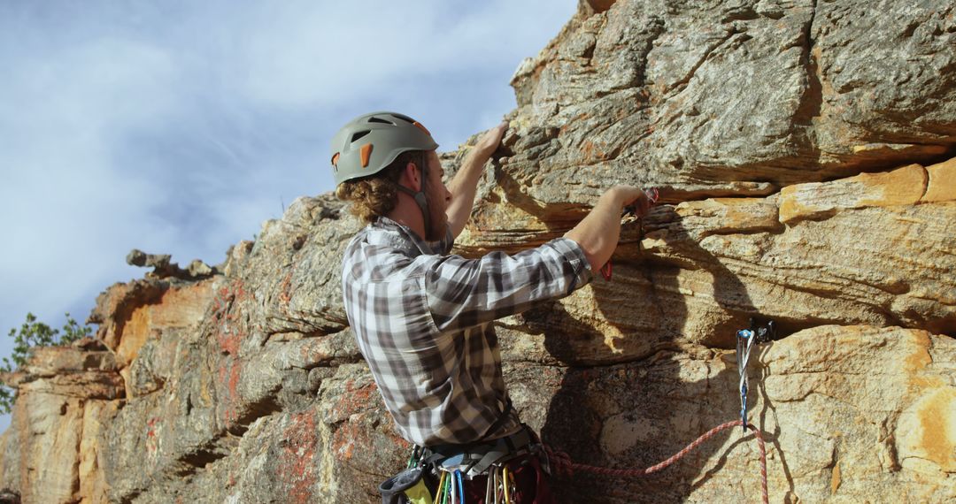 Male Climber Securing Route on Rocky Cliff Edge in Harness and Helmet - Free Images, Stock Photos and Pictures on Pikwizard.com