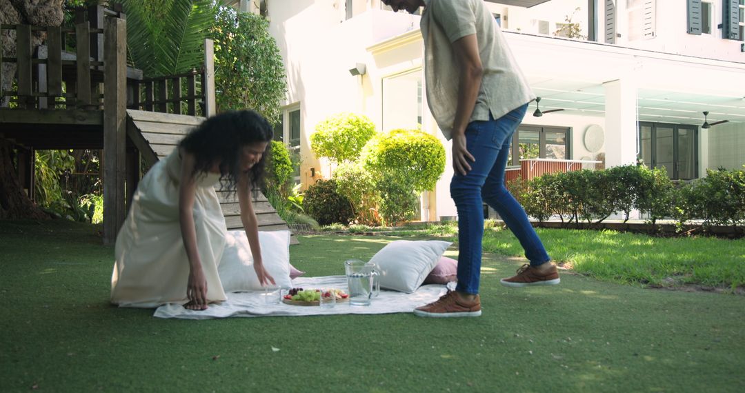 Couple Setting Picnic Blanket in Lush Garden