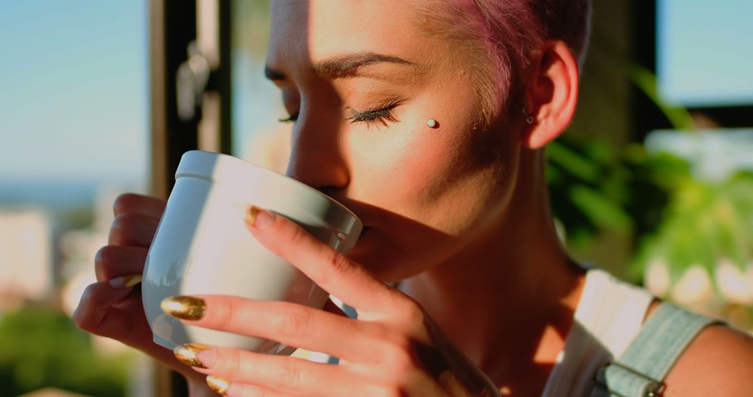 Close-up of Woman Sipping Coffee in Sunlight with Pink Hair and Piercing - Free Images, Stock Photos and Pictures on Pikwizard.com