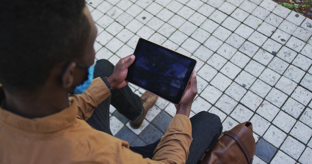 Young Man Using Tablet Outdoors on Brick Pavement - Free Images, Stock Photos and Pictures on Pikwizard.com