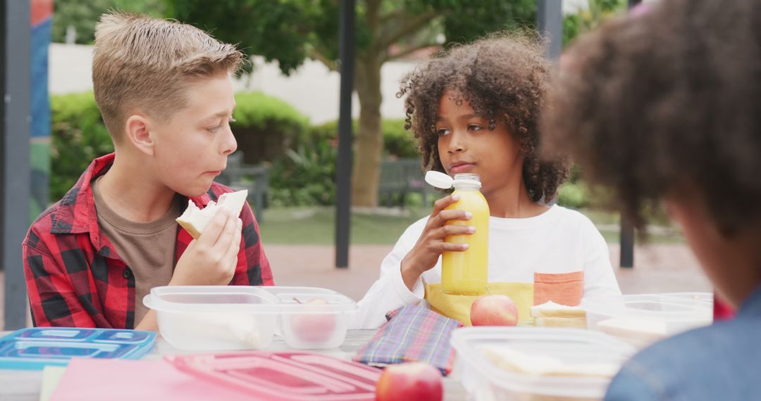 Two Diverse Boys Enjoying Packed Lunch in Schoolyard