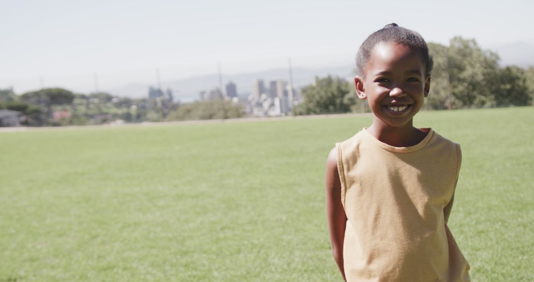 Smiling African American Child in Open Field with Cityscape Background - Free Images, Stock Photos and Pictures on Pikwizard.com