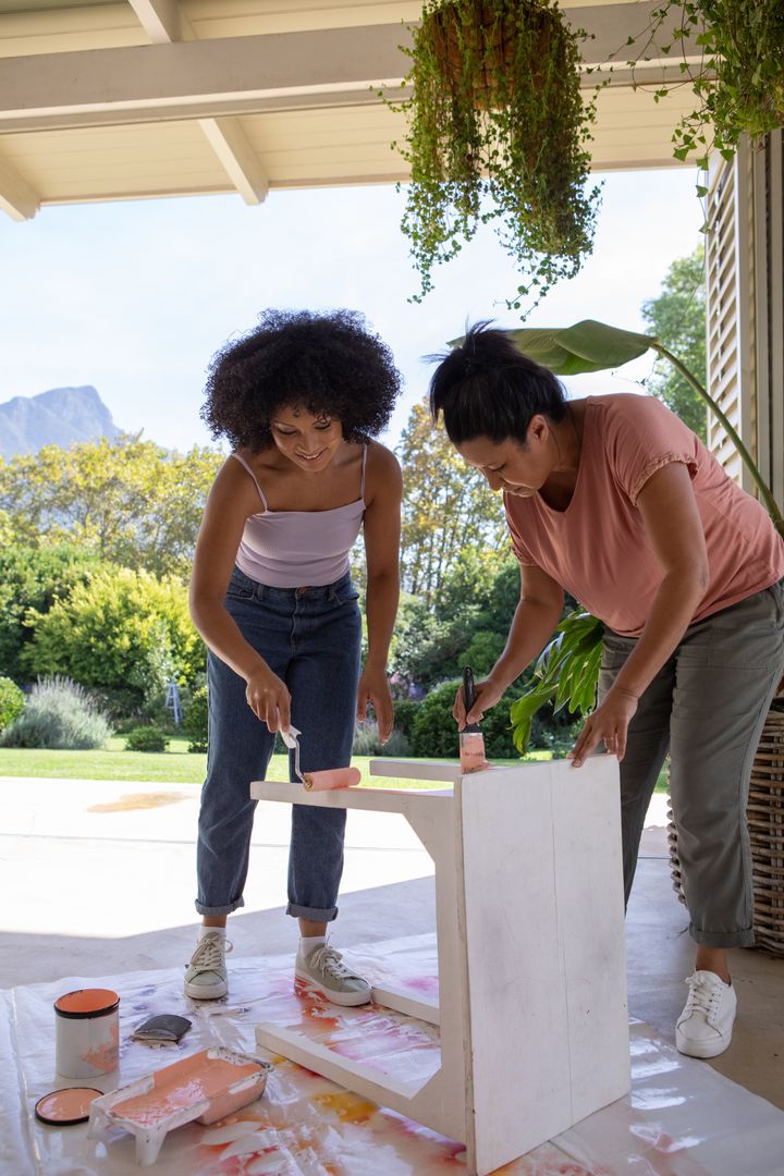 Mother and Daughter Painting Wooden Table on Patio