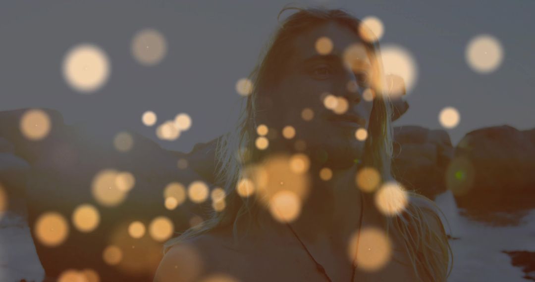 Shirtless Man with Dumbbells on Rocky Shore at Dusk with Artistic Bokeh