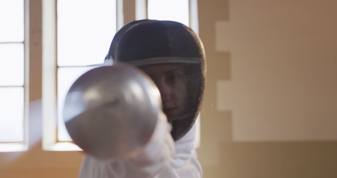 Fencer in Protective Gear Holding Foil in Sunlit Room - Free Images, Stock Photos and Pictures on Pikwizard.com