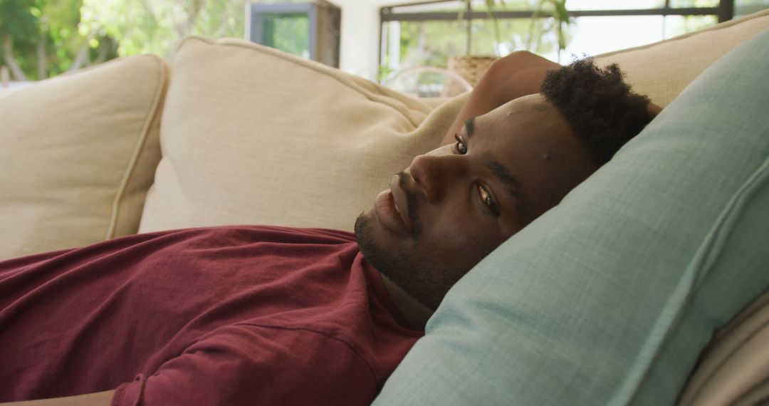 Image of relaxed african american man lying on sofa - Free Images, Stock Photos and Pictures on Pikwizard.com