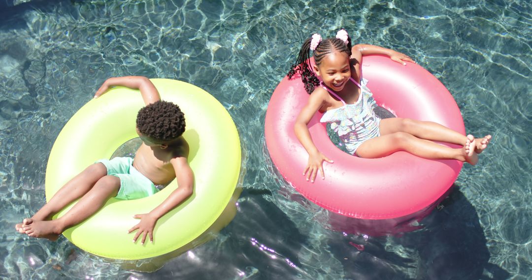 Happy African American Children Floating on Inflatable Rings in Swimming Pool - Free Images, Stock Photos and Pictures on Pikwizard.com