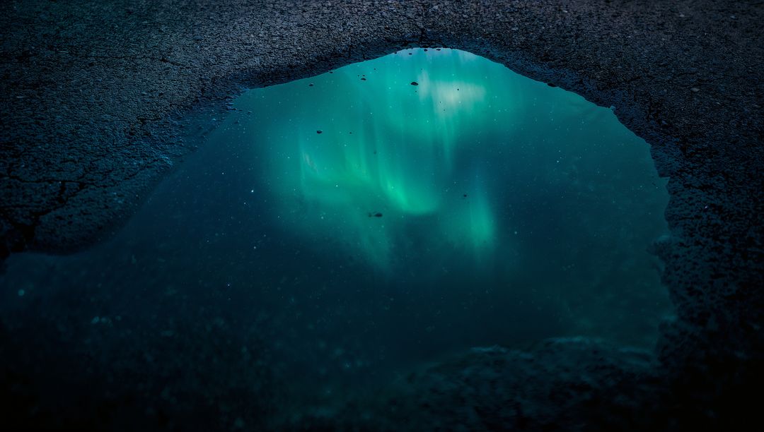 Reflecting Puddle Capturing Green Aurora Over Cracked Asphalt Night Sky Reflection Glow
