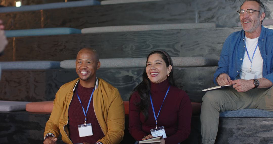 Diverse team laughing and taking notes during modern conference in tiered auditorium