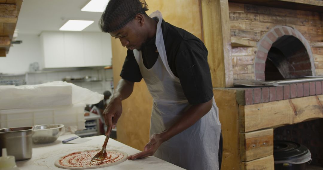 Chef Spreading Sauce on Pizza Dough in Rustic Pizzeria - Free Images, Stock Photos and Pictures on Pikwizard.com