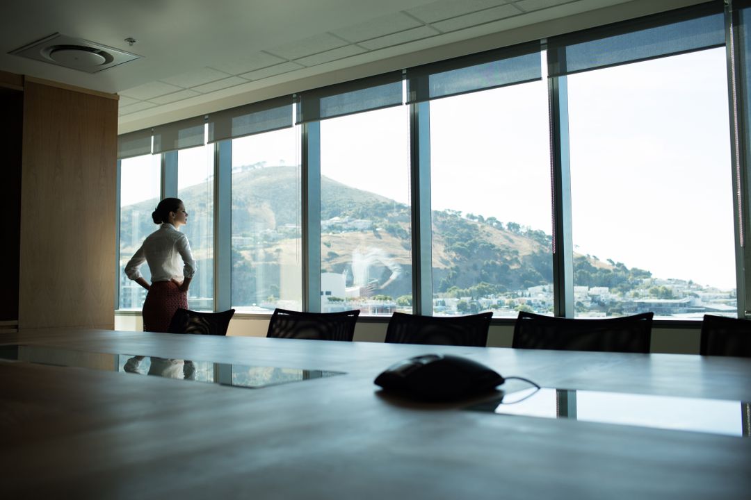 Businesswoman Looking Through Window in Conference Room - Free Images, Stock Photos and Pictures on Pikwizard.com