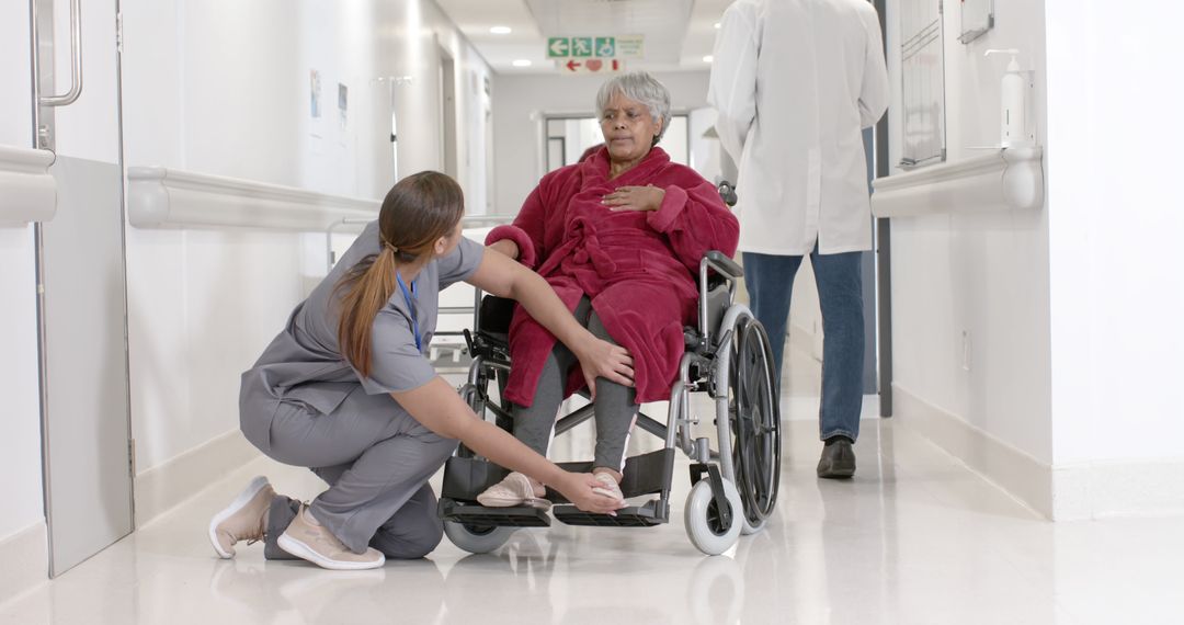 Nurse Assisting Senior Woman in Red Robe in Wheelchair in Hospital - Free Images, Stock Photos and Pictures on Pikwizard.com