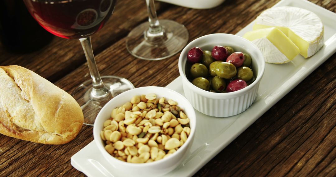 Gourmet Snack Plate with Wine, Olives, Nuts, and Cheese on Rustic Table - Free Images, Stock Photos and Pictures on Pikwizard.com