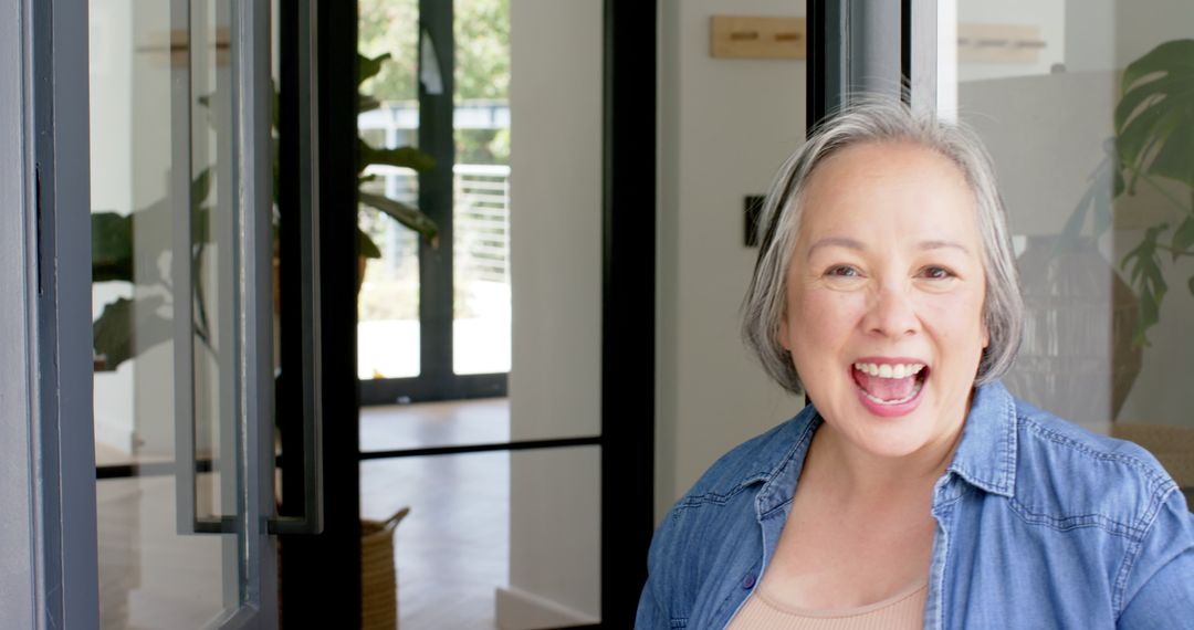Senior Woman Smiling Warmly While Opening Glass Door