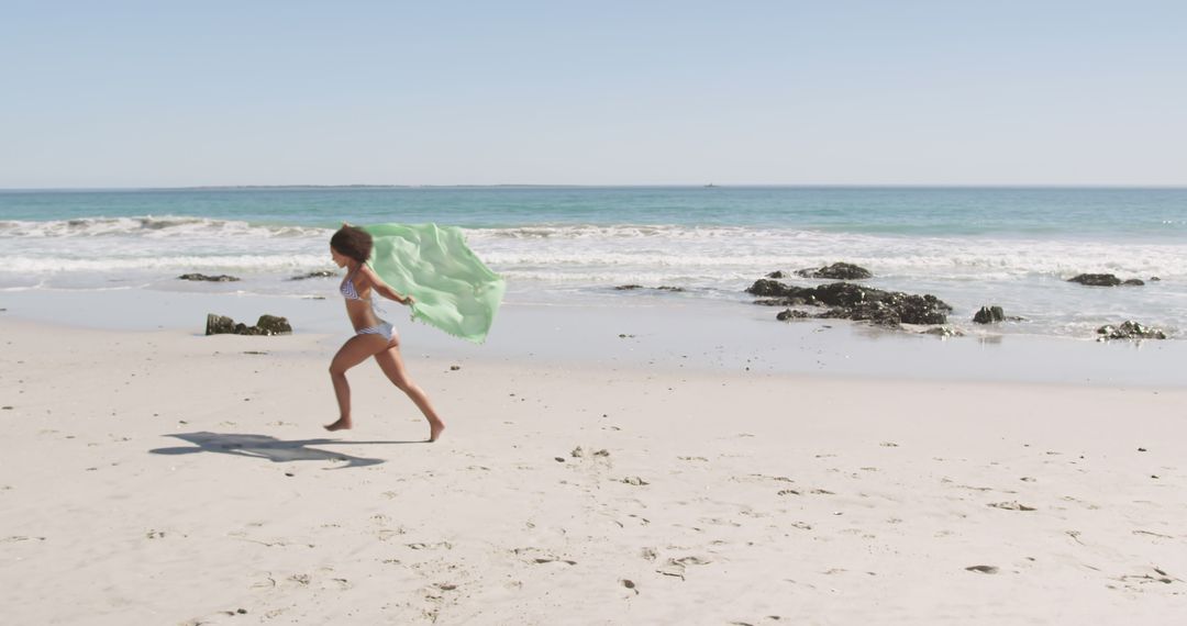 Child Running on Beach with Green Scarf on Sunny Day - Free Images, Stock Photos and Pictures on Pikwizard.com