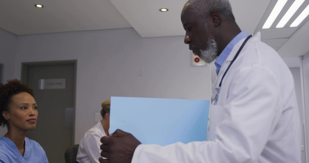 Doctor Holding Patient File Consulting Nursing Team in Clinical Healthcare Environment