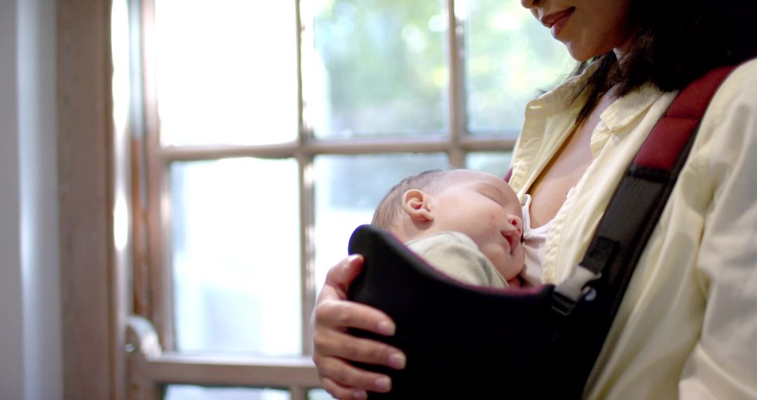 Mother Cradling Newborn in Baby Carrier at Home