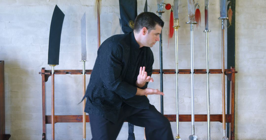 Martial Artist Practicing Traditional Forms with Stage Weapons Displayed - Free Images, Stock Photos and Pictures on Pikwizard.com