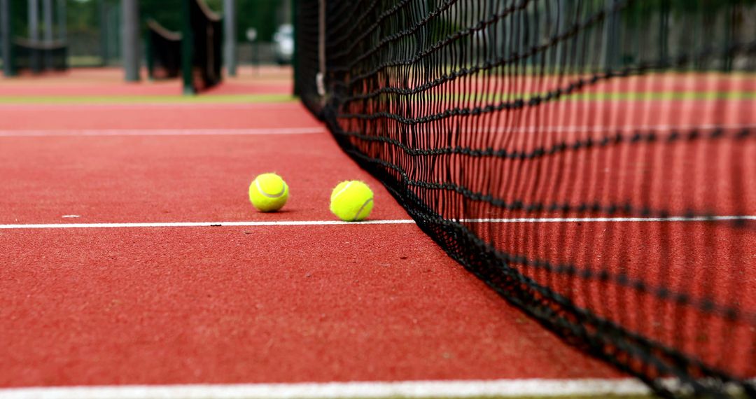 Tennis Balls on Red Court Next to Net - Free Images, Stock Photos and Pictures on Pikwizard.com