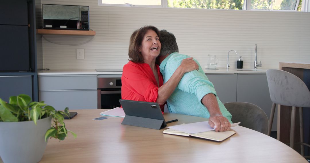 Senior Couple Embracing and Discussing Documents with Tablet